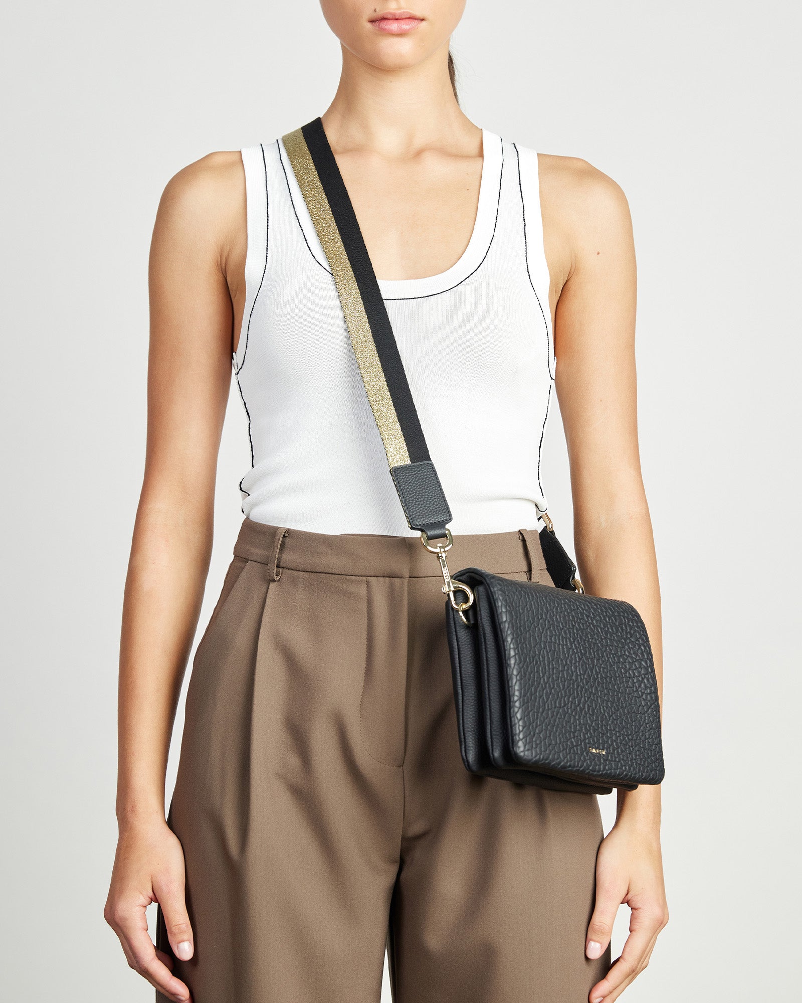 A striped feature strap with black, gold and white colors, with leather trim and gold-plated hardware, fully adjustable.