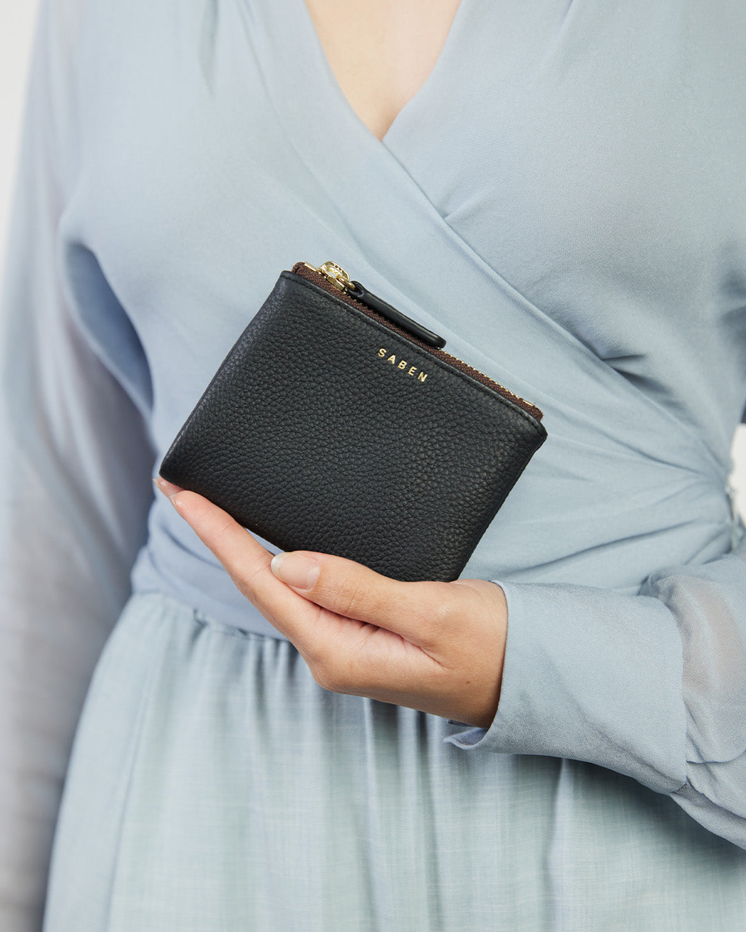 A compact black leather wallet with gold-plated hardware, featuring multiple card slots, a zippered coin pouch, and other compartments.