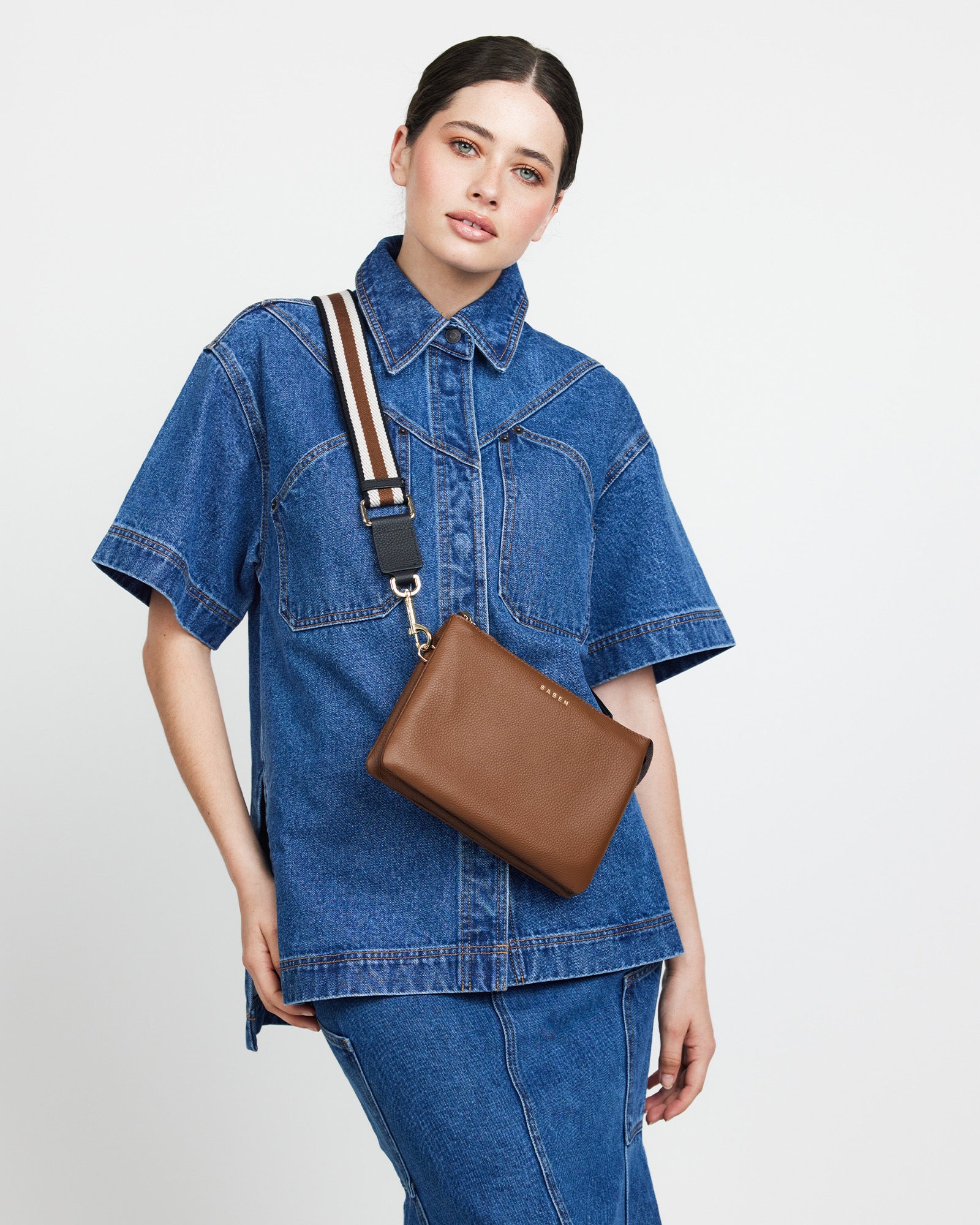 Striped bag strap with gold hardware on a white background