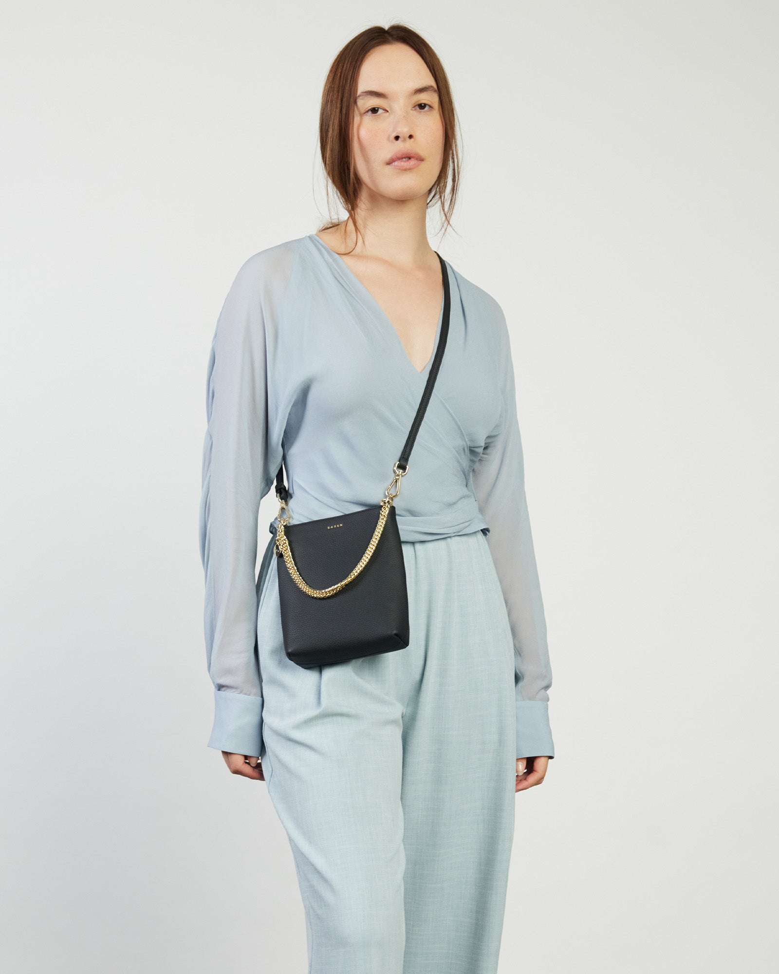 A black quilted leather handbag with a structured shape and a detachable chain strap, featuring gold hardware.