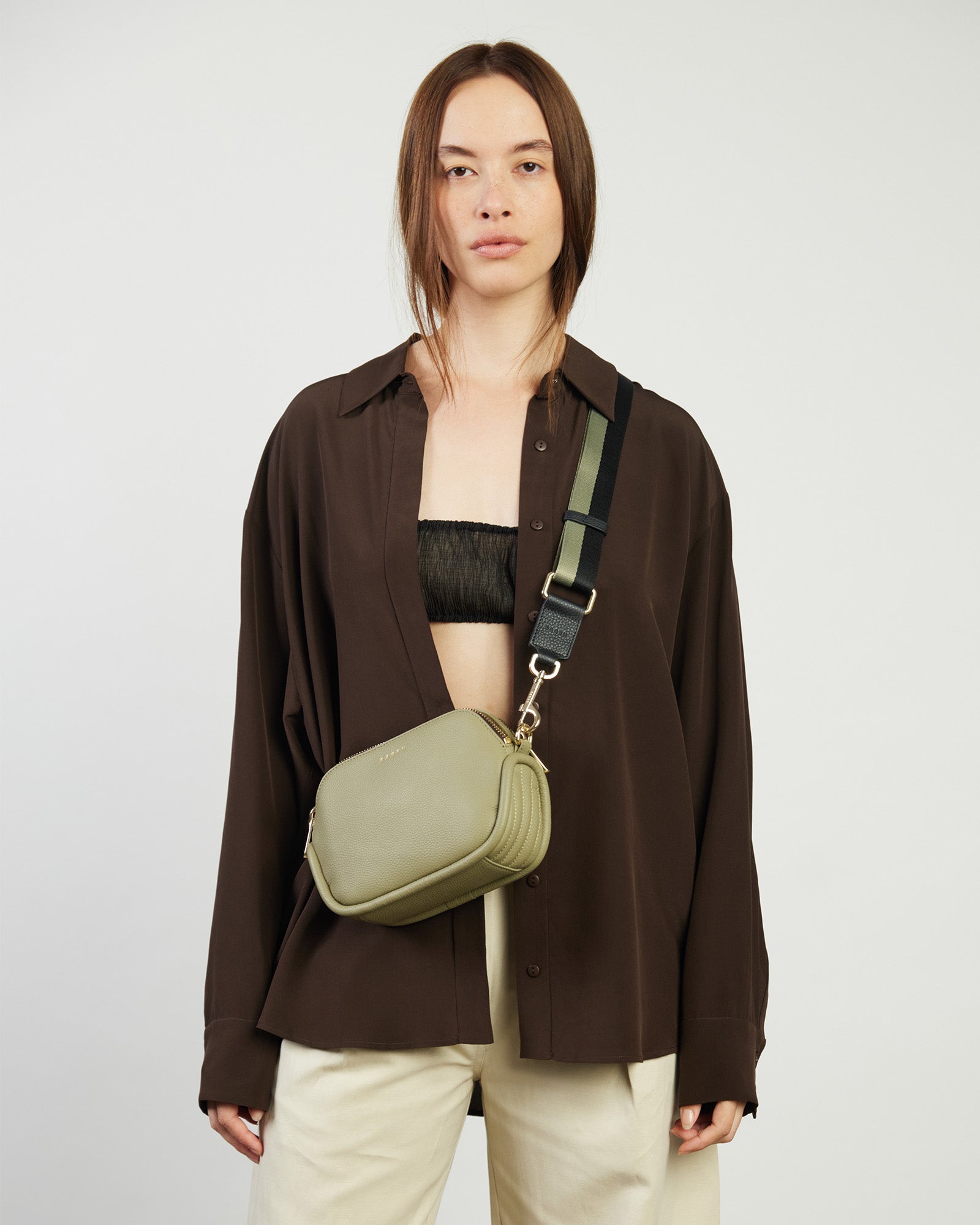 Two-tone bag strap with gold hardware on a white background