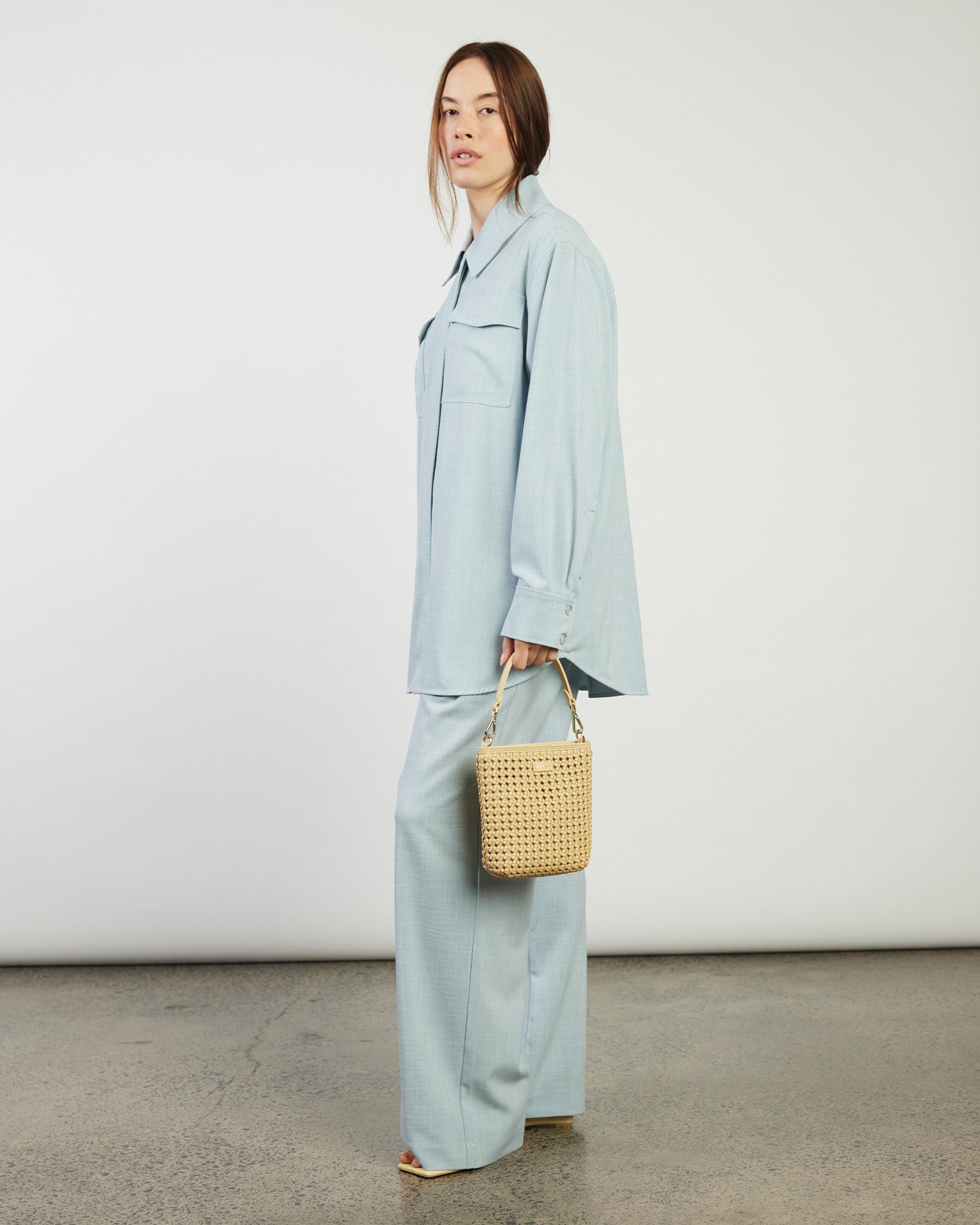 Beige woven handbag with a strap on a white background