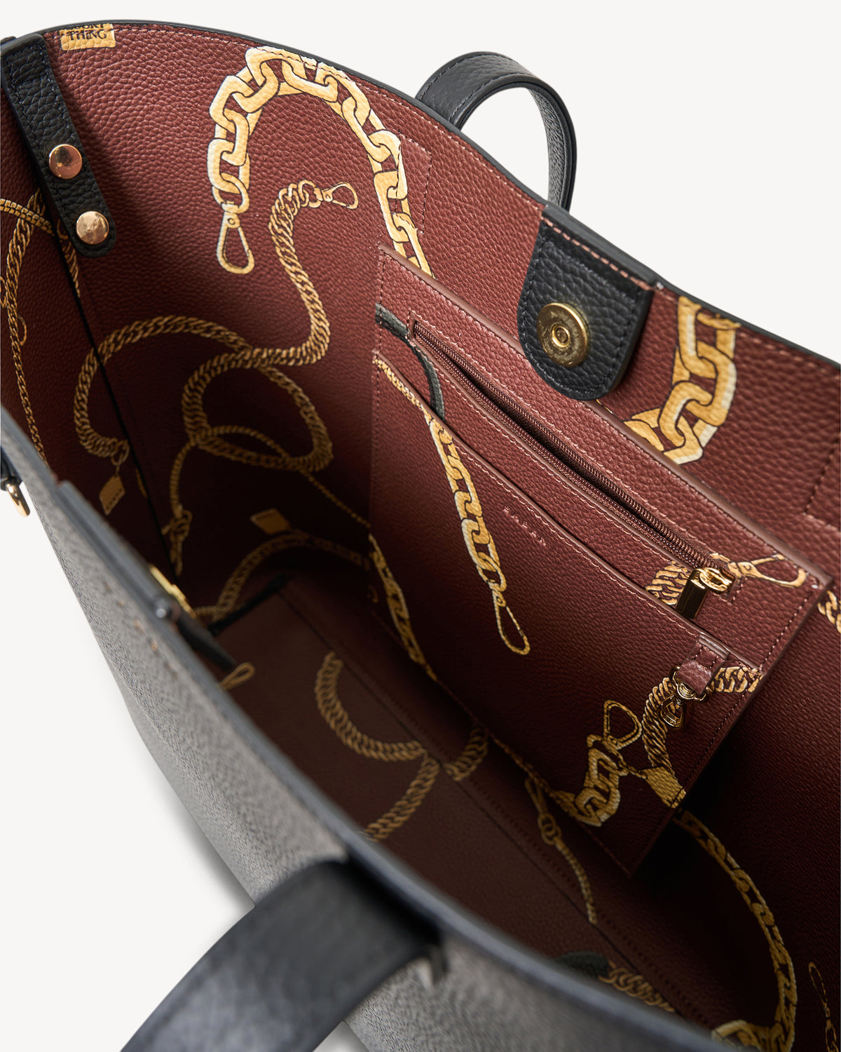 Close-up of a leather handbag with gold chain design on a white background