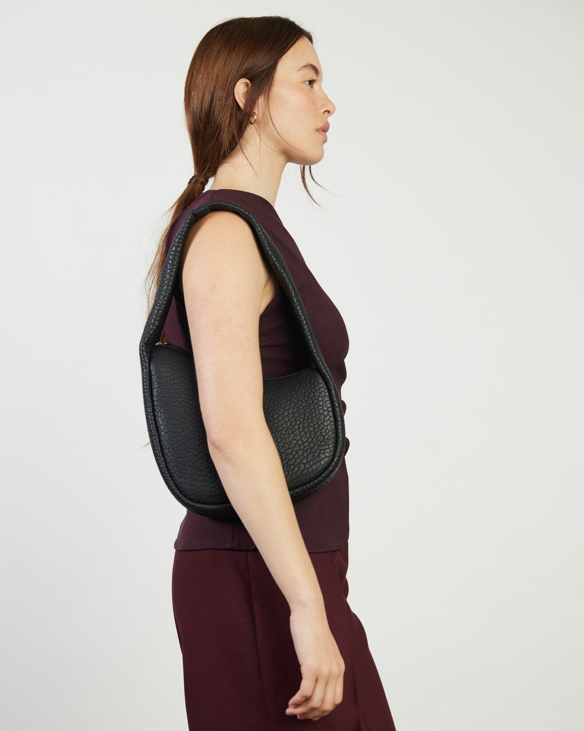 Woman wearing a black backpack on a plain background