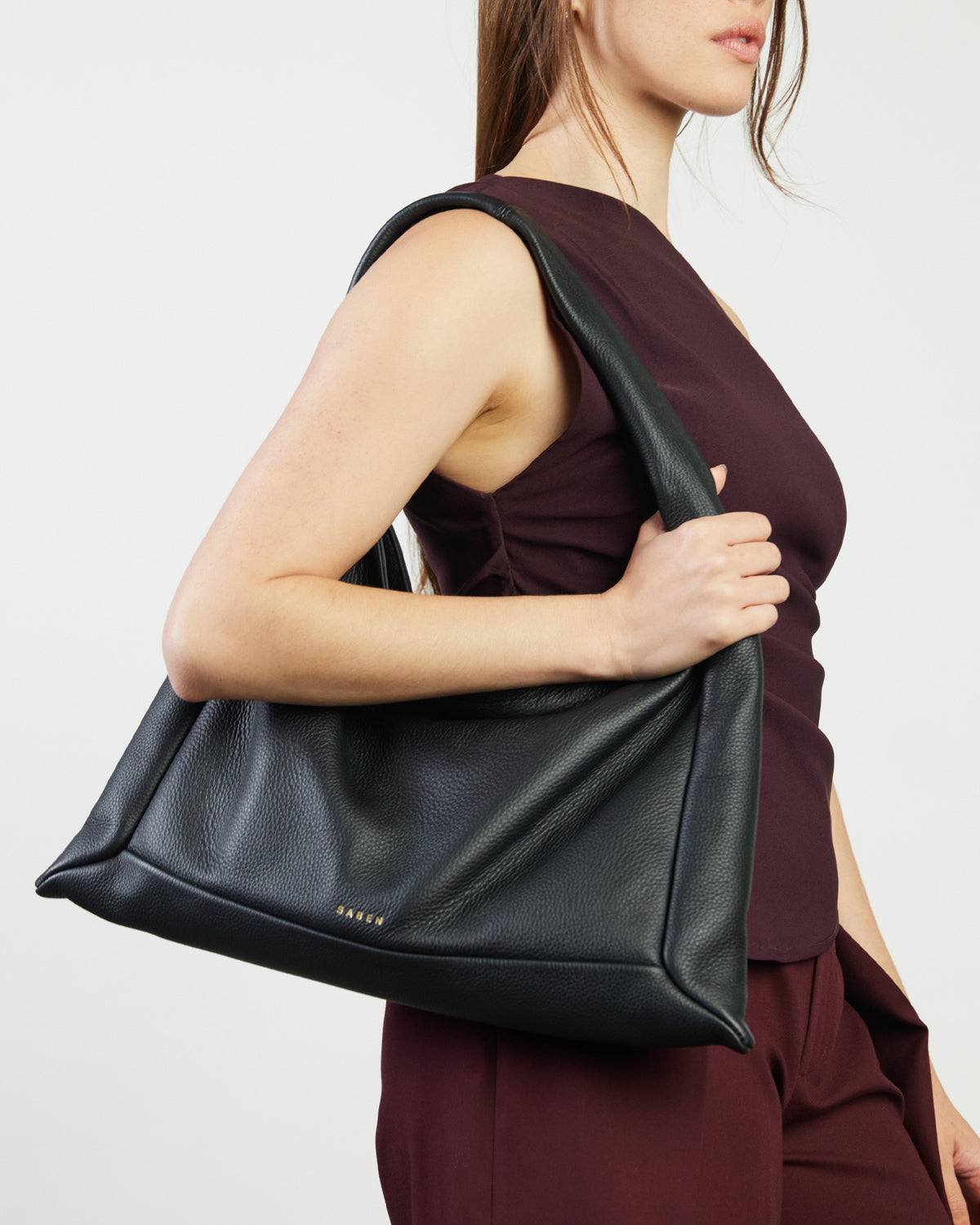 Woman holding a black leather bag against a white background