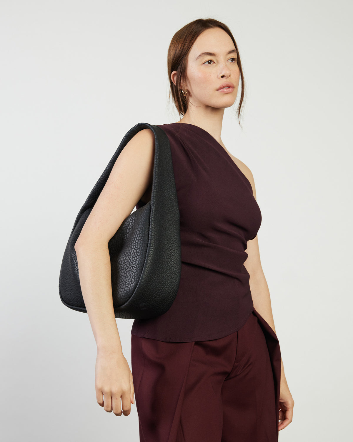 Woman carrying a black handbag against a plain background