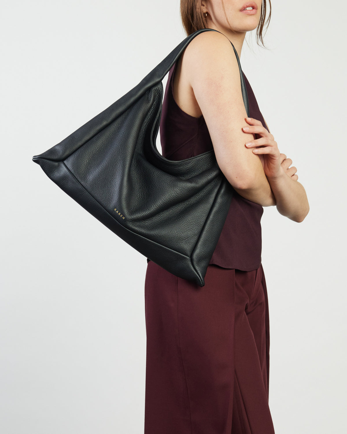 Person wearing a black leather handbag on a plain background