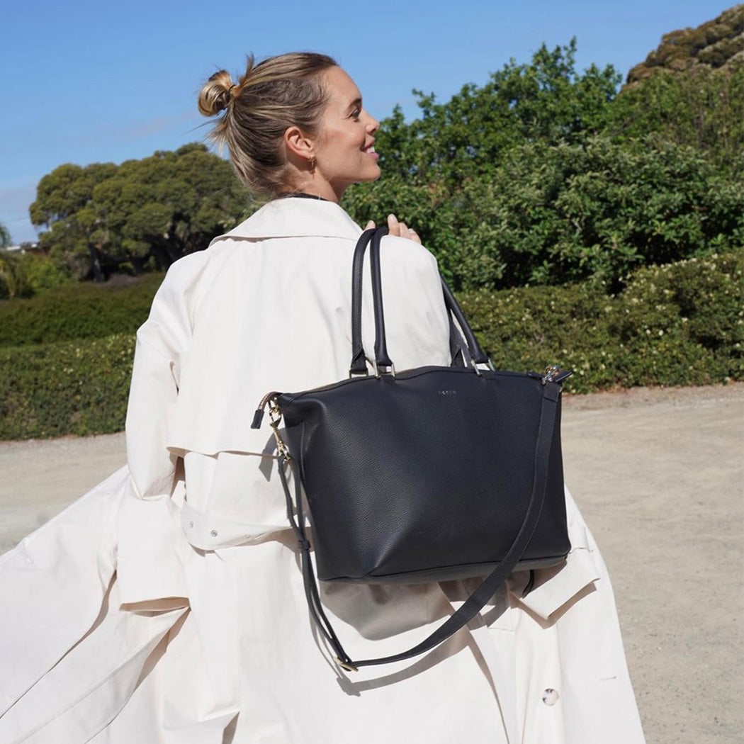 a women holding a Black handbag with gold accents on a white background