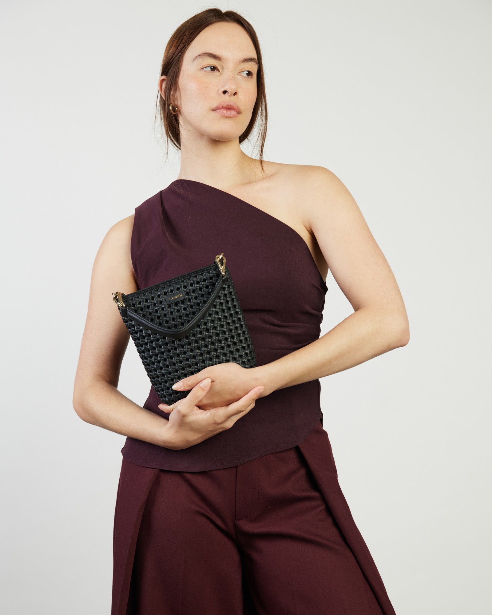 Black woven handbag with gold accents on a white background