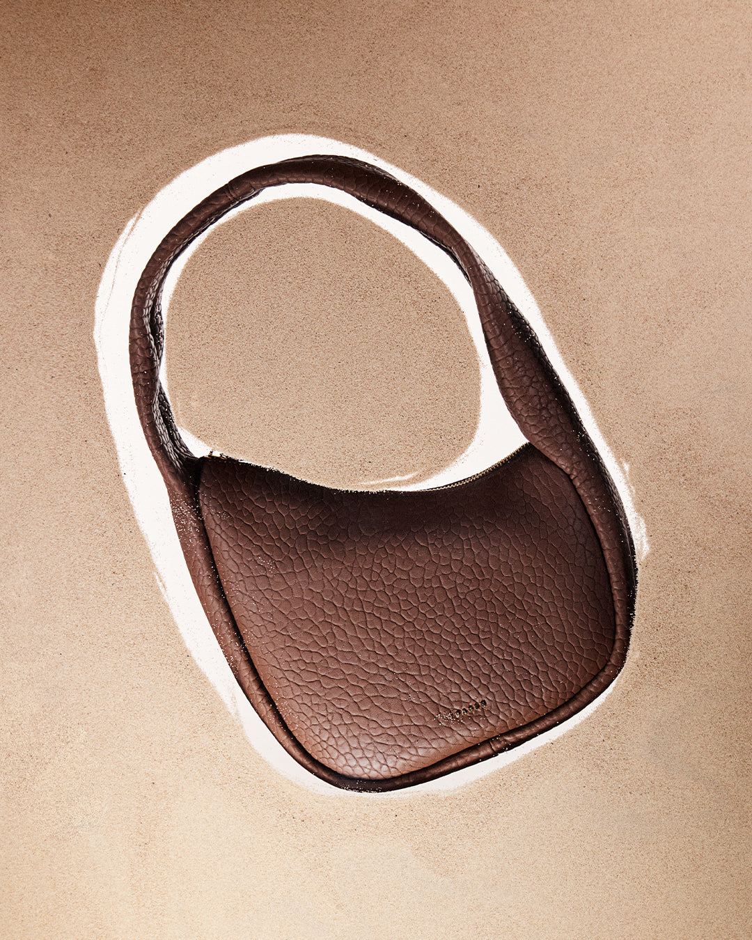 Brown leather bag on a beige background
