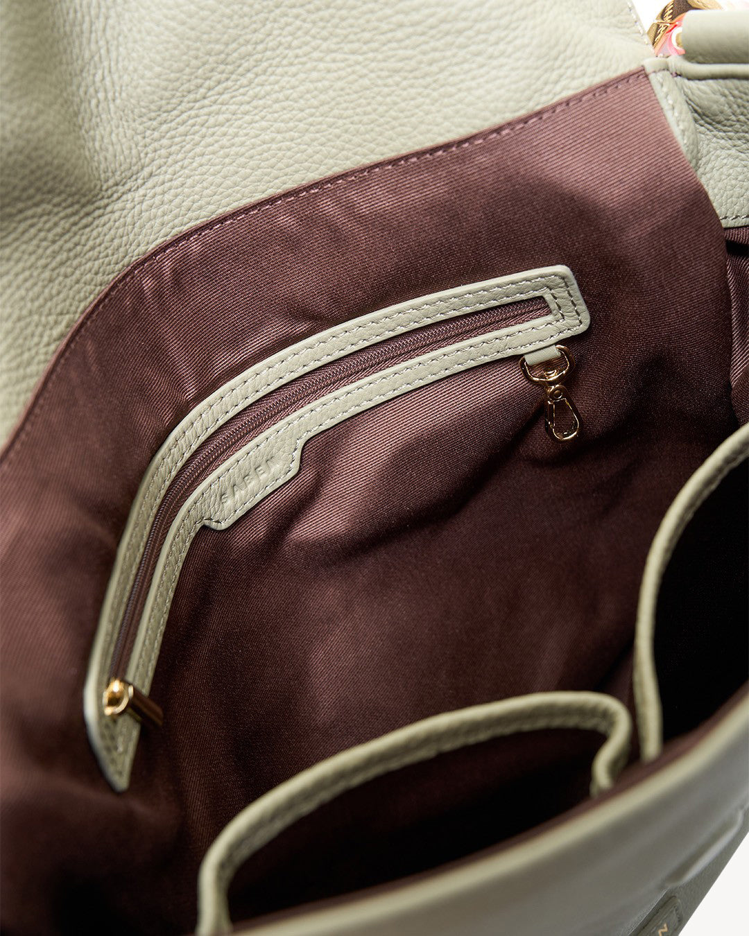 Close-up of a brown zipper on a bag with beige interior