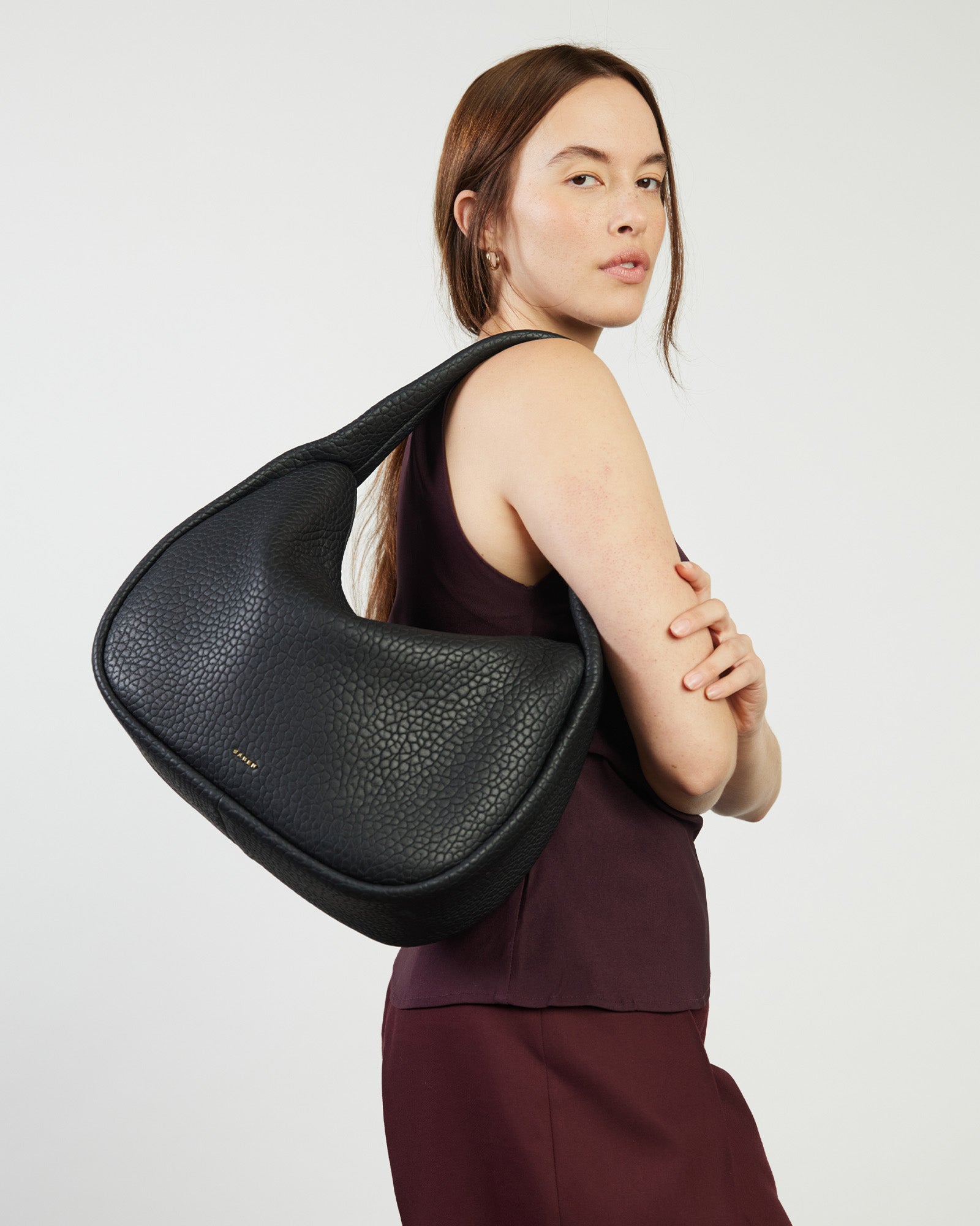A black leather hobo-style shoulder bag with a wide shoulder strap and a bubble-textured surface.