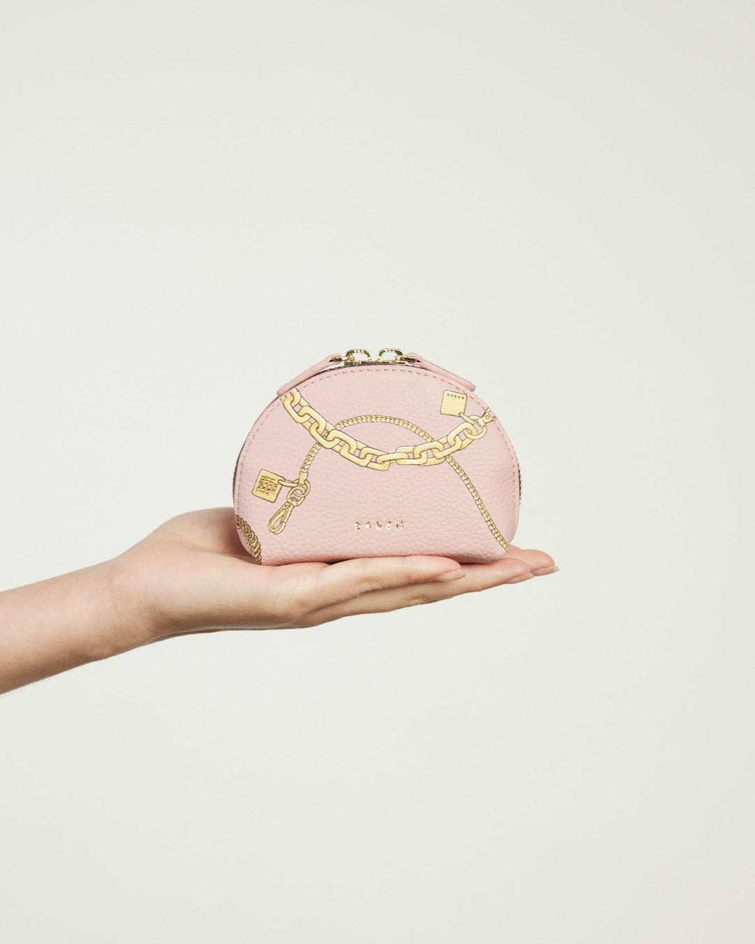 Pink cosmetic bag with gold chain detail on a white background